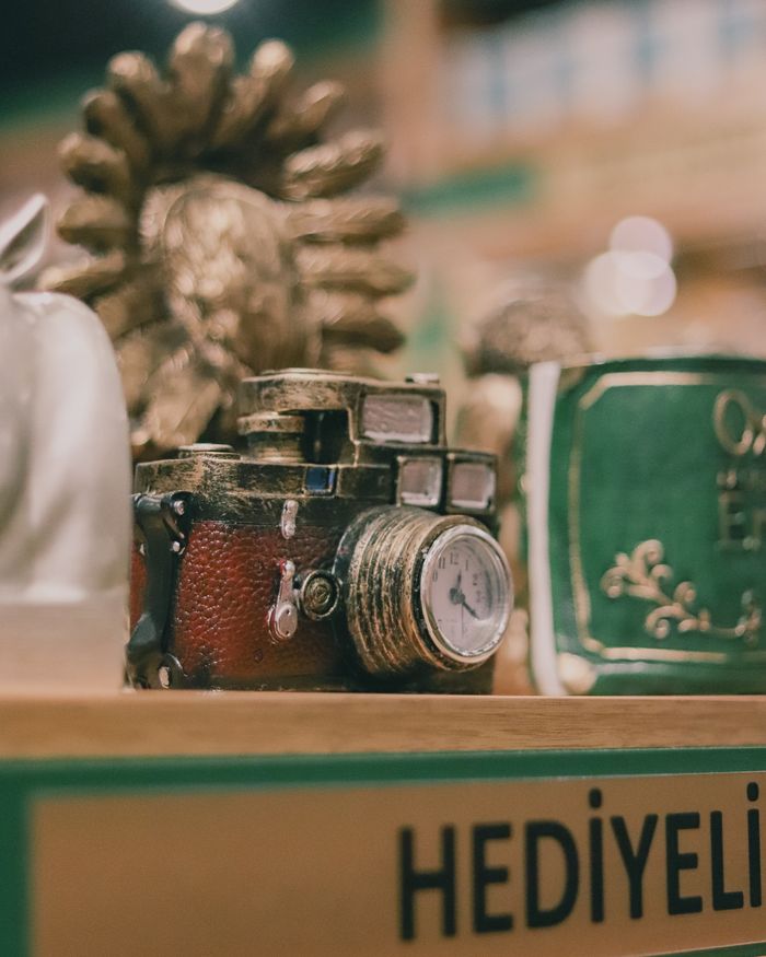 A detailed shot highlighting a vintage camera styled as a clock, featuring artistic decor and a sunburst backdrop in a shop setting.