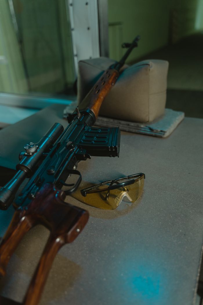 Detailed view of a sniper rifle with safety glasses on a shooting range table.